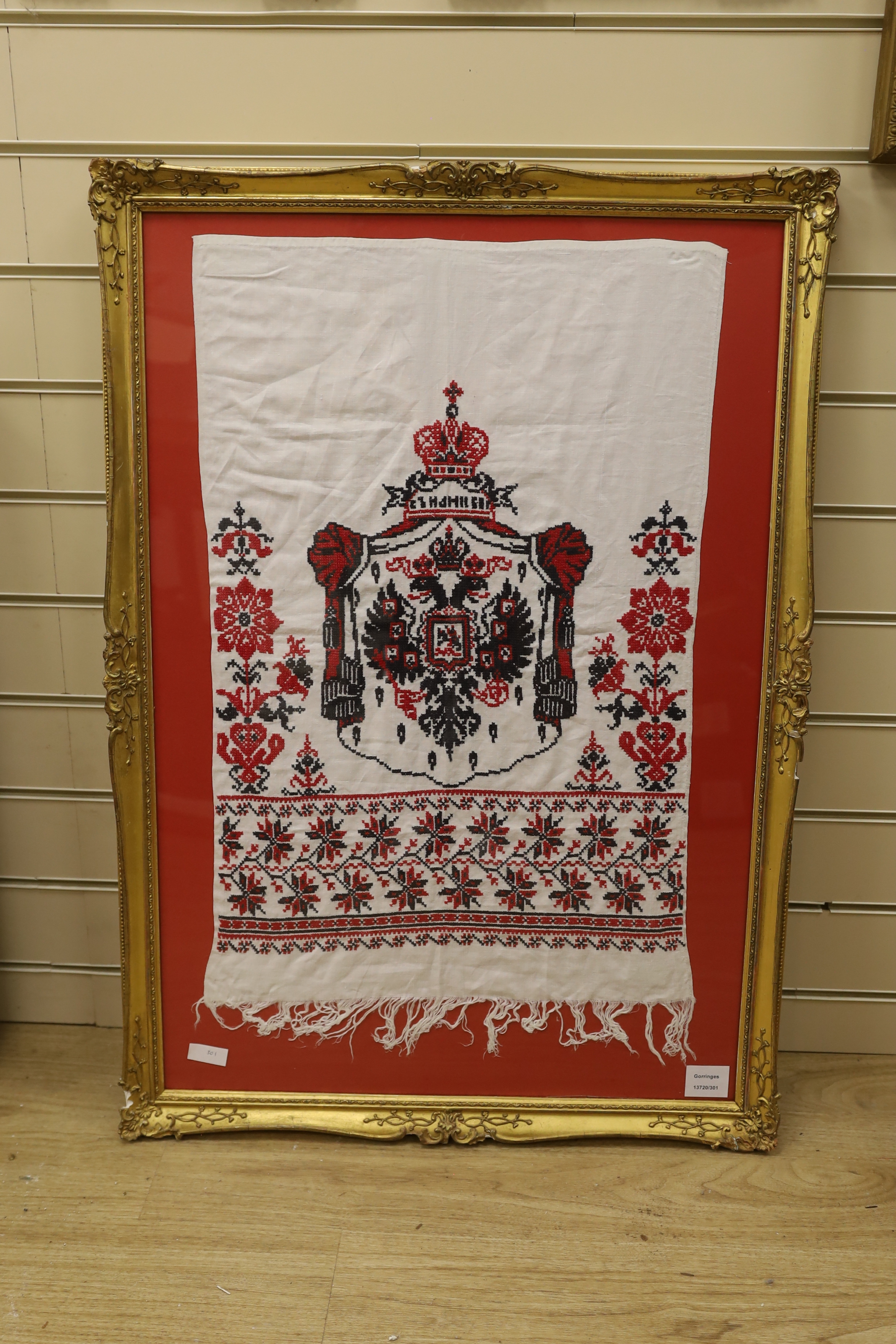 A framed Russian red and black cross stitch embroidered linen hanging of the Romanov coat of arms
